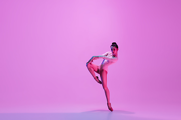 Image showing Young and graceful ballet dancer isolated on pink studio background in neon light. Art, motion, action, flexibility, inspiration concept.