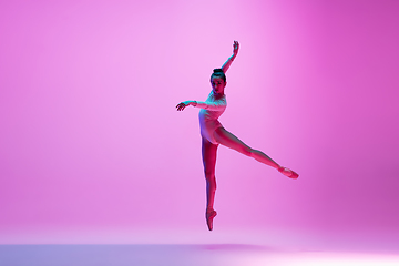 Image showing Young and graceful ballet dancer isolated on pink studio background in neon light. Art, motion, action, flexibility, inspiration concept.