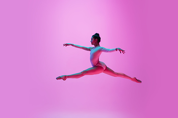 Image showing Young and graceful ballet dancer isolated on pink studio background in neon light. Art, motion, action, flexibility, inspiration concept.