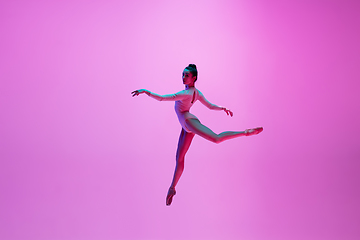 Image showing Young and graceful ballet dancer isolated on pink studio background in neon light. Art, motion, action, flexibility, inspiration concept.