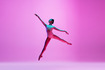 Image showing Young and graceful ballet dancer isolated on pink studio background in neon light. Art, motion, action, flexibility, inspiration concept.