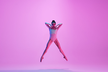 Image showing Young and graceful ballet dancer isolated on pink studio background in neon light. Art, motion, action, flexibility, inspiration concept.