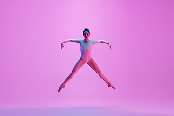 Image showing Young and graceful ballet dancer isolated on pink studio background in neon light. Art, motion, action, flexibility, inspiration concept.