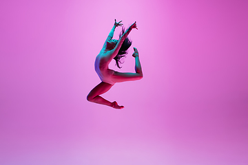 Image showing Young and graceful ballet dancer isolated on pink studio background in neon light. Art, motion, action, flexibility, inspiration concept.