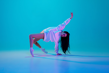 Image showing Young and graceful ballet dancer isolated on blue studio background in neon light. Art, motion, action, flexibility, inspiration concept.