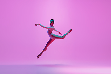 Image showing Young and graceful ballet dancer isolated on pink studio background in neon light. Art, motion, action, flexibility, inspiration concept.