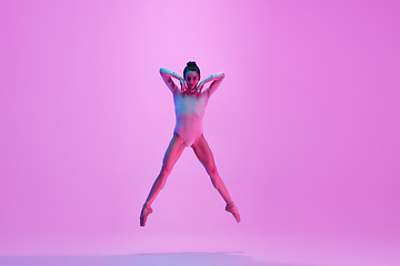 Image showing Young and graceful ballet dancer isolated on pink studio background in neon light. Art, motion, action, flexibility, inspiration concept.