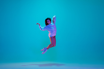 Image showing Young and graceful ballet dancer isolated on blue studio background in neon light. Art, motion, action, flexibility, inspiration concept.