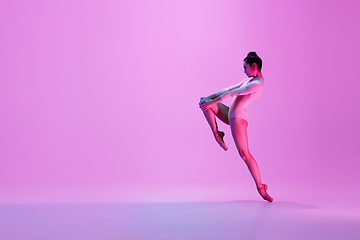 Image showing Young and graceful ballet dancer isolated on pink studio background in neon light. Art, motion, action, flexibility, inspiration concept.