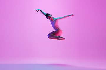 Image showing Young and graceful ballet dancer isolated on pink studio background in neon light. Art, motion, action, flexibility, inspiration concept.