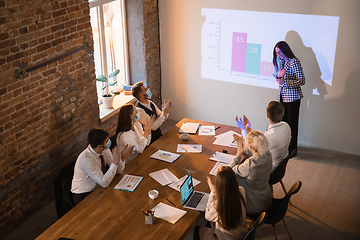 Image showing Female speaker giving presentation in hall at workshop. Audience or conference hall. Participants, co-workers listening at the table.