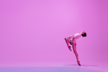 Image showing Young and graceful ballet dancer isolated on pink studio background in neon light. Art, motion, action, flexibility, inspiration concept.