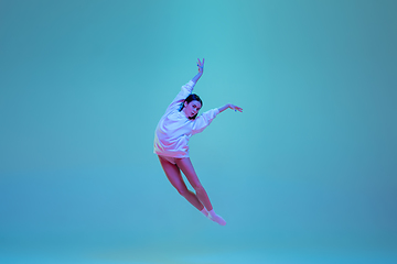 Image showing Young and graceful ballet dancer isolated on blue studio background in neon light. Art, motion, action, flexibility, inspiration concept.