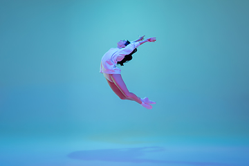 Image showing Young and graceful ballet dancer isolated on blue studio background in neon light. Art, motion, action, flexibility, inspiration concept.