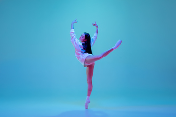 Image showing Young and graceful ballet dancer isolated on blue studio background in neon light. Art, motion, action, flexibility, inspiration concept.