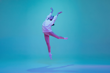 Image showing Young and graceful ballet dancer isolated on blue studio background in neon light. Art, motion, action, flexibility, inspiration concept.