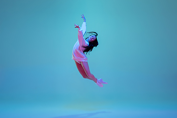 Image showing Young and graceful ballet dancer isolated on blue studio background in neon light. Art, motion, action, flexibility, inspiration concept.