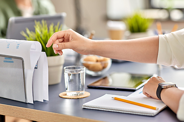 Image showing businesswoman reaching to paper at office