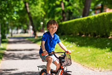 Image showing happy little boy riding bicycle at summer park