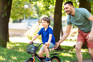 Image showing father teaching little son to ride bicycle at park