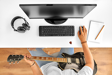 Image showing young man with computer and guitar at table