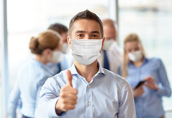 Image showing businessman in mask showing thumbs up at office