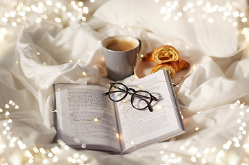 Image showing croissants, cup of coffee, book and glasses in bed