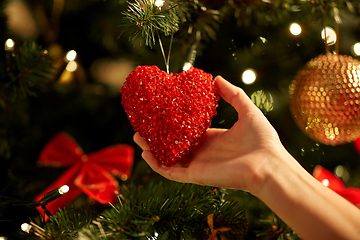 Image showing hands decorating christmas tree with red heart