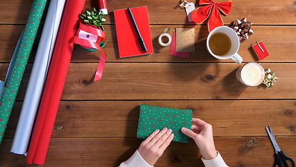 Image showing hands wrapping christmas gift into paper at home