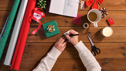 Image showing hands attaching name tag to christmas gift