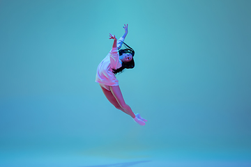 Image showing Young and graceful ballet dancer isolated on blue studio background in neon light. Art, motion, action, flexibility, inspiration concept.