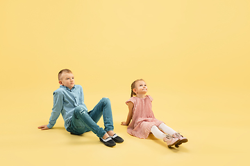 Image showing Childhood and dream about big and famous future. Boy and girl isolated on yellow studio background