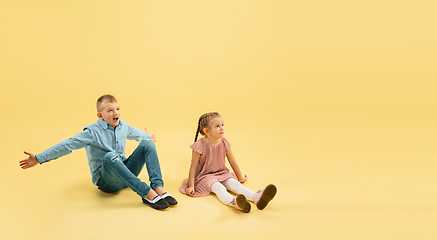 Image showing Childhood and dream about big and famous future. Boy and girl isolated on yellow studio background