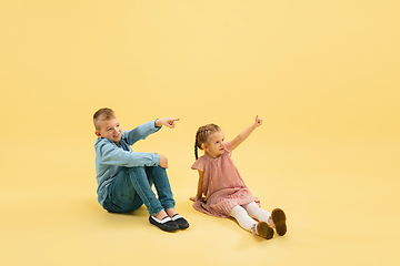 Image showing Childhood and dream about big and famous future. Boy and girl isolated on yellow studio background