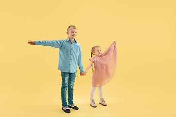 Image showing Childhood and dream about big and famous future. Boy and girl isolated on yellow studio background