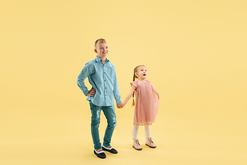 Image showing Childhood and dream about big and famous future. Boy and girl isolated on yellow studio background