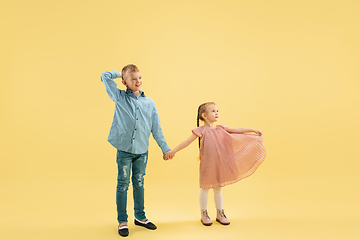 Image showing Childhood and dream about big and famous future. Boy and girl isolated on yellow studio background