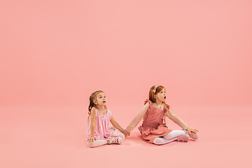 Image showing Childhood and dream about big and famous future. Pretty little girls isolated on coral pink background