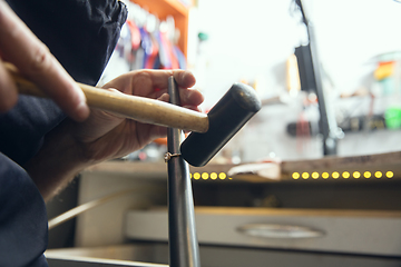 Image showing Close up hands of jeweller, goldsmiths making of golden ring with gemstone using professional tools.