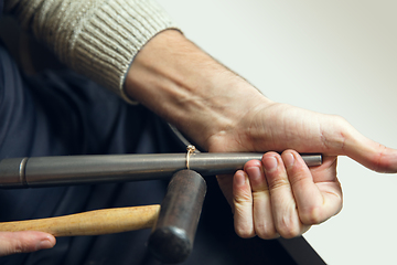 Image showing Close up hands of jeweller, goldsmiths making of golden ring with gemstone using professional tools.