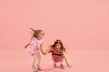 Image showing Childhood and dream about big and famous future. Pretty little girls isolated on coral pink background