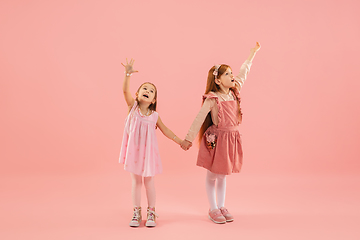 Image showing Childhood and dream about big and famous future. Pretty little girls isolated on coral pink background