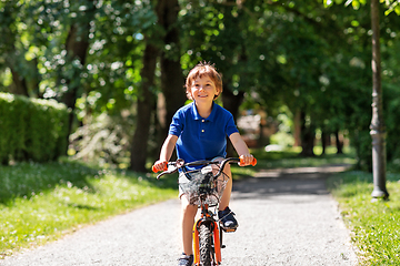 Image showing happy little boy riding bicycle at summer park