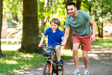 Image showing father teaching little son to ride bicycle at park