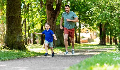 Image showing happy father and son compete in running at park