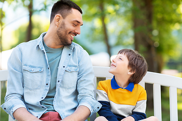 Image showing father with son sitting on park bench and talking