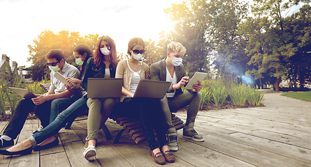 Image showing teenage students in masks with computers at campus