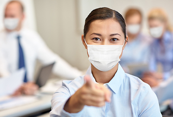 Image showing businesswoman in mask pointing finger at office