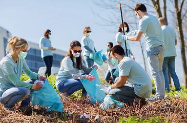 Image showing volunteers in masks with bags cleaning outdoors