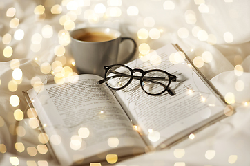 Image showing cup of coffee, book, glasses and garland in bed